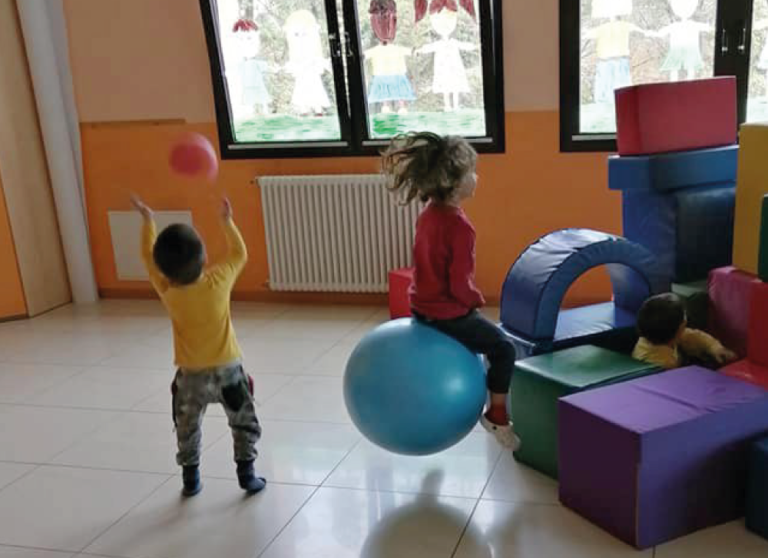 Bambini che giocano con palle nel salone dell'Asilo Valli.