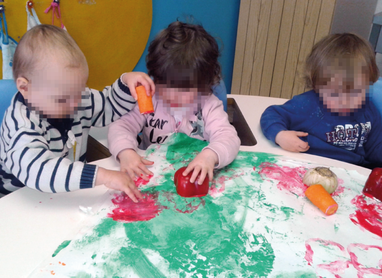 Bambini del Nido integrato dipingono con tempere e verdura.