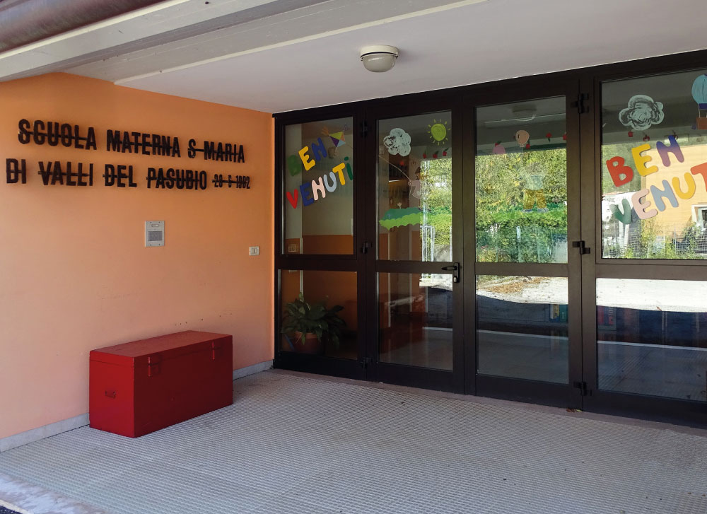 Porta dell'entrata della scuola dell'infanzia Santa Maria di Valli del Pasubio, con scritte colorate di benvenuto.