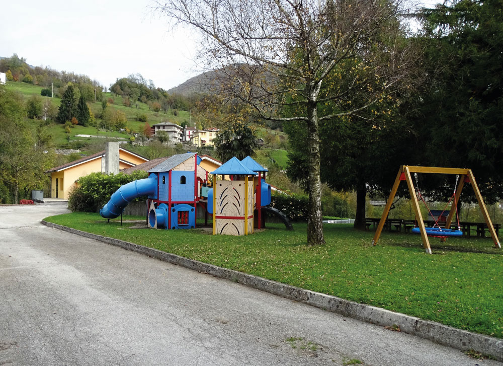 Parco giochi con giostre dell'Asilo Valli, immerso nel verde.